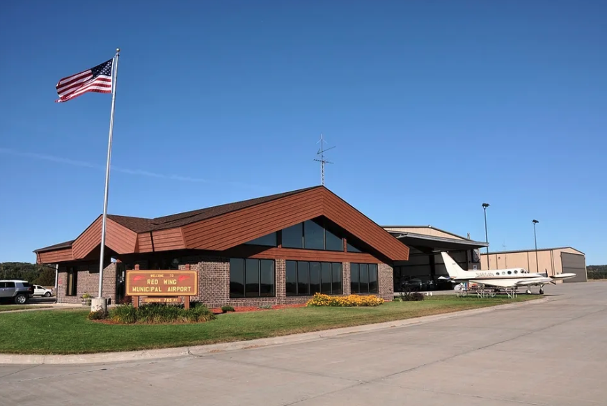 Photo of Red Wing Airport building with plane and American flag. Located in Hager City, WI